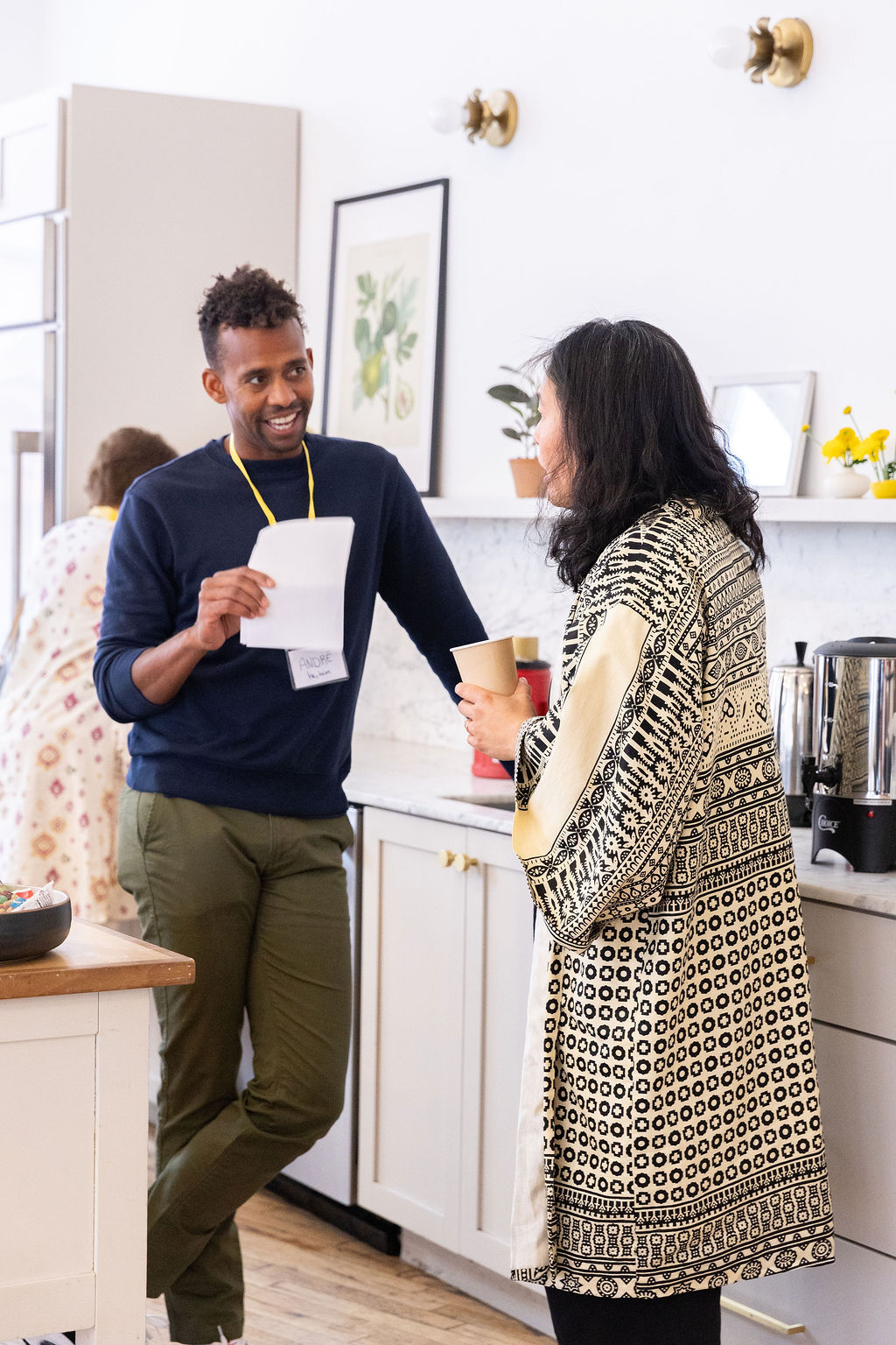 Andre Essue talking with a participant beside a kitchen counter during a session break.
